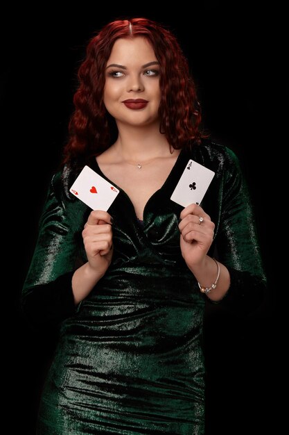 Donna sexy dai capelli rossi in posa con carte da gioco in mano, su sfondo nero