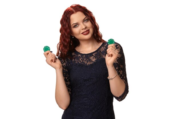 Sexy redheaded woman with a curly hair is posing with some blue chips in her hands poker