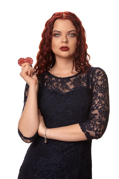 Sexy redheaded woman with a curly hair is posing with some red chips in her hands. Poker