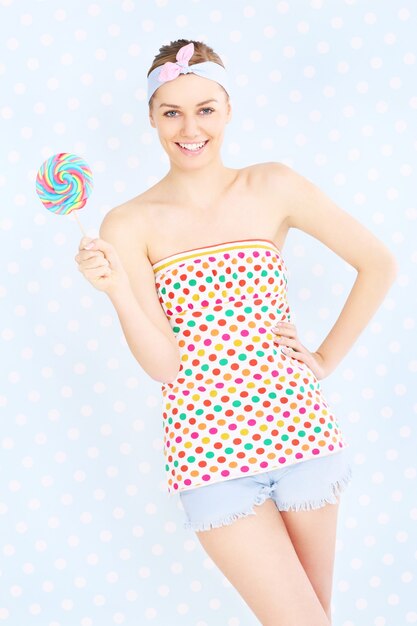 a sexy retro woman posing with a lollipop over white and blue dotted background