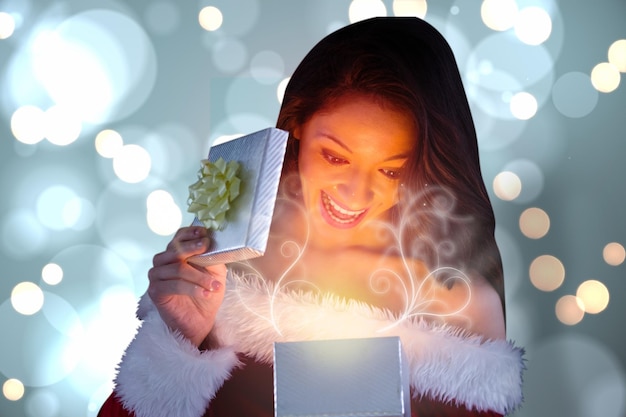 Photo sexy santa girl opening gift against white glowing dots on blue