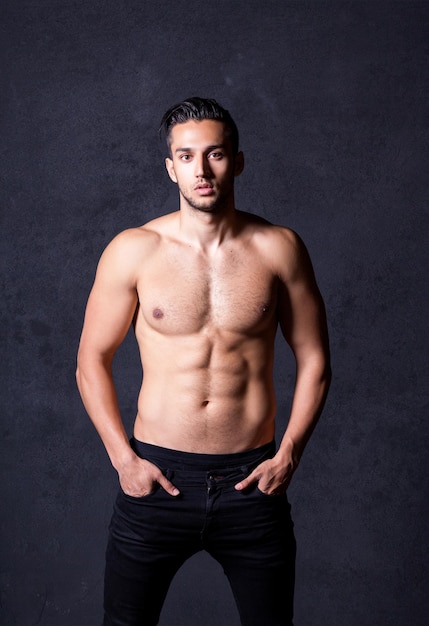 Sexy shirtless male model flirting against black background