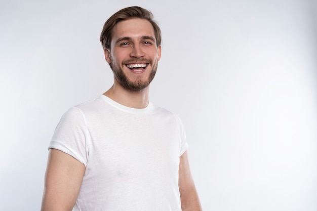 Sexy smiling handsome man in white t-shirt isolated on white.