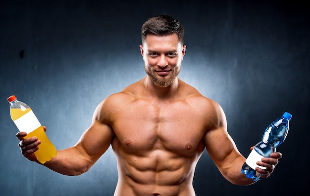 Sexy sportsman holding a bottle of water and soda.