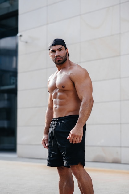 Sexy sportsman stands topless near the wall. Fitness, bodybuilding
