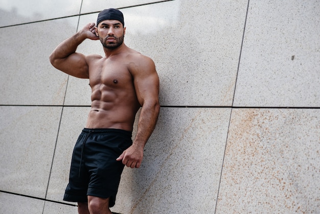 Sexy sportsman stands topless near the wall. Fitness, bodybuilding.