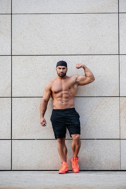 Sexy sportsman stands topless near the wall. Fitness, bodybuilding