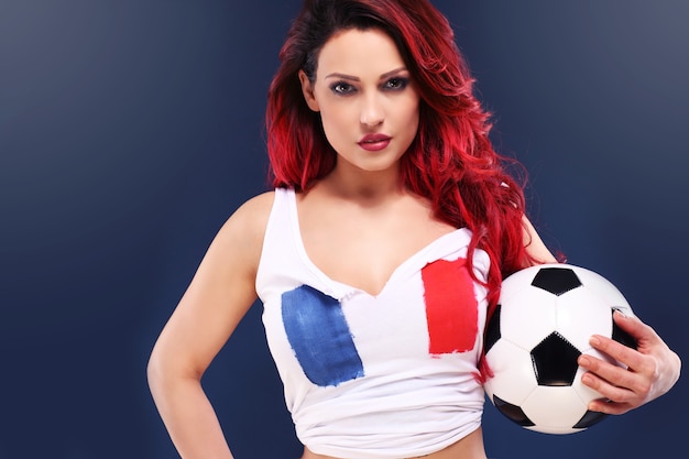 sexy vrouw die Franse vlag draagt en voetbal houdt