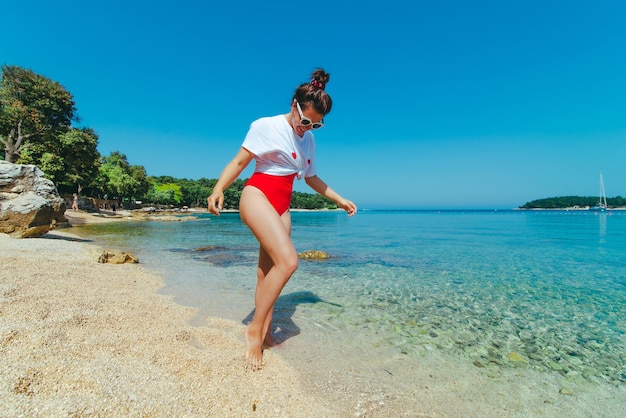 Sexy vrouw in rood zwempak en wit t-shirt op zeestrand