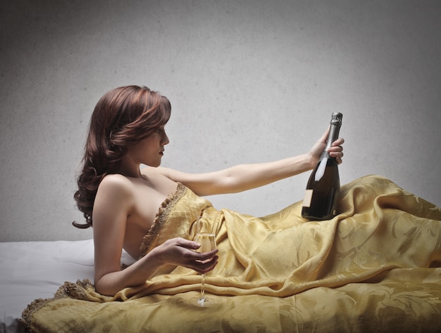 Sexy vrouw met champagne in bed