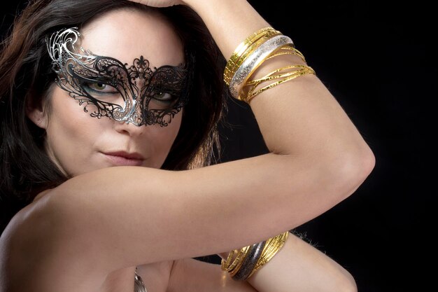 Sexy vrouw met venetiaans masker en gouden en zilveren armbanden