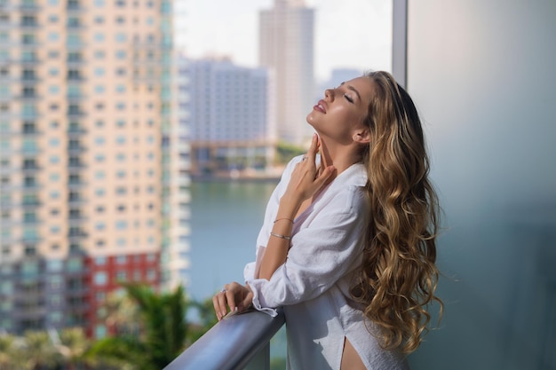 Sexy vrouw op terras jongedame in stijlvol shirt poseert op balkon en geniet van lentemeisje op