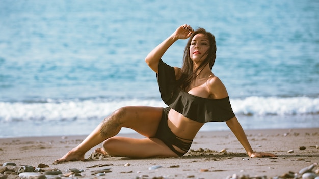 Sexy vrouw zittend op het strand in een bikini