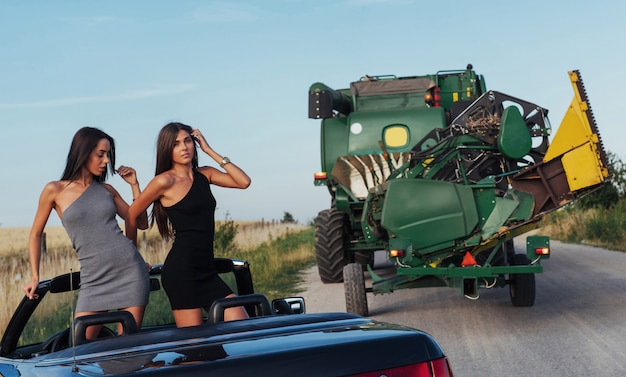 Sexy vrouwen die in een zwarte converteerbare auto stellen