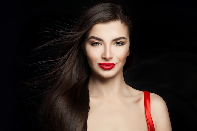 Sexy woman brunette with dark straight hair and red lips makeup Happy girl on black background