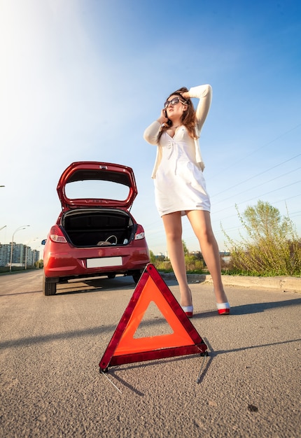 Sexy woman calling mechanic after car breakdown