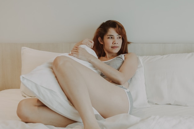 セクシーな女性は部屋の中で一人でベッドでリラックスを感じます