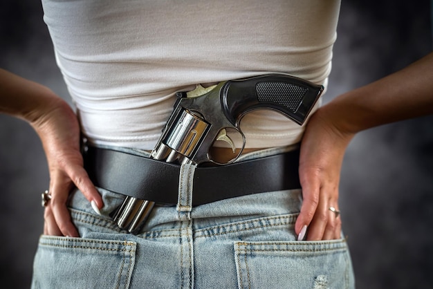 Sexy woman hides a gun behind her back behind her belt or near her leg