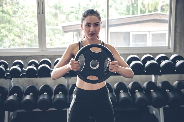 Sexy woman holding dumbbells in the modern gym in exercise  concept.