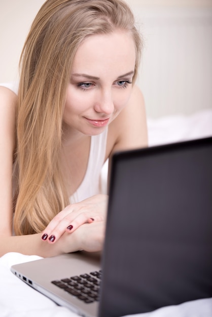 A sexy woman lying on the bed with laptop.