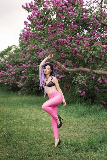 sexy woman  in pink leather pants is standing under the lilac