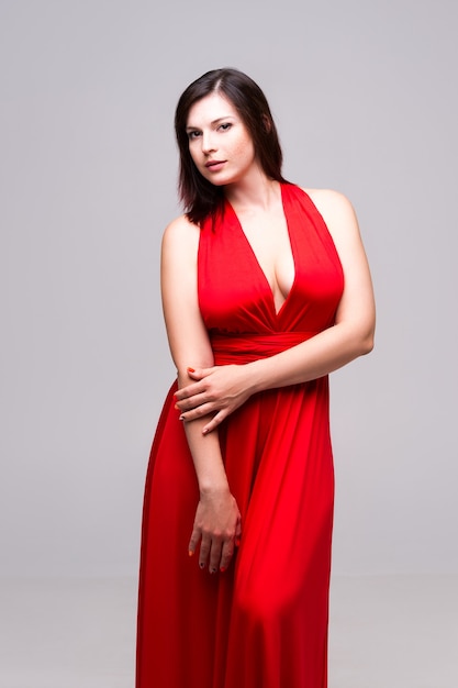 Sexy woman in red dress with deep neckline  on gray wall,