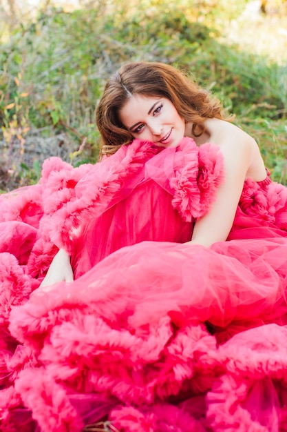 Sexy woman in red dress with fluffy skirt posing outdoors