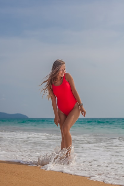 Donna sexy in costume da bagno rosso sulla spiaggia