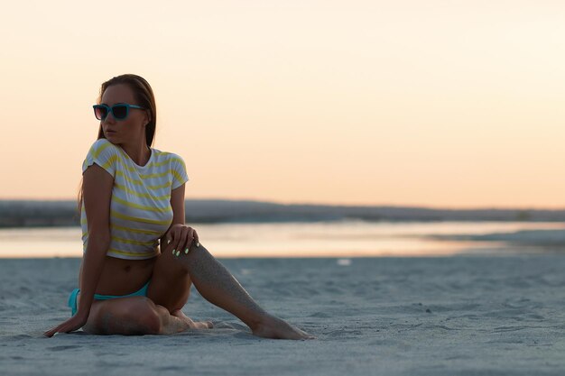 Sexy woman in t shirt sitting on beach