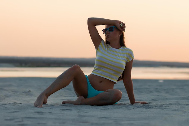 Sexy woman in t shirt sitting on beach