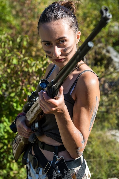 Sexy woman in top holing gun rifle wild nature hunting\
concept