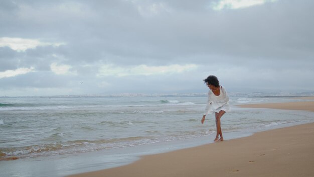 Sexy woman walking ocean coastline alone happy carefree girl touching sand