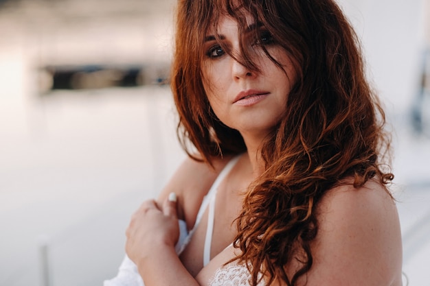 Sexy woman in a white shirt enjoys the sunset on her private white yacht