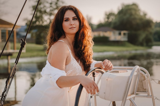 Sexy woman in a white shirt enjoys the sunset on her private white yacht.