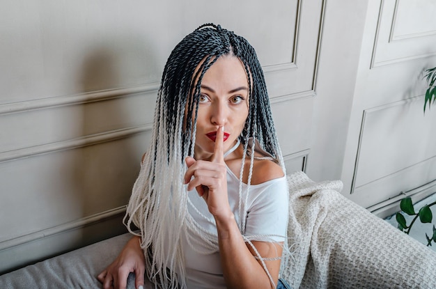 Sexy woman with afro braids Gesture to be quiet Secret Gray studio background