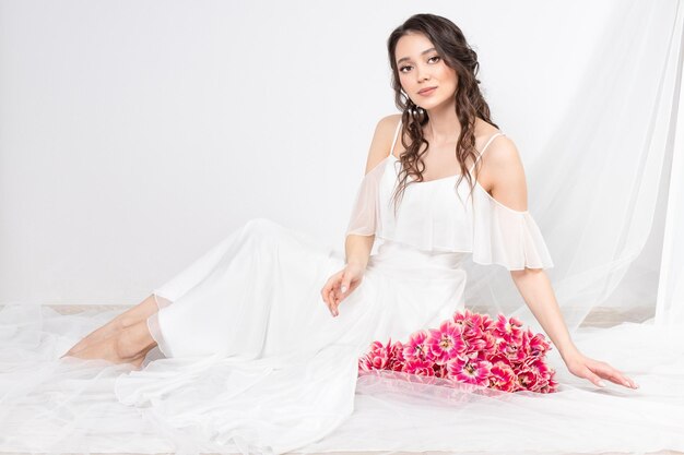 Sexy woman with flowers pink tulips in hands on a light background