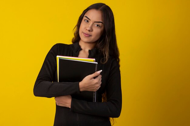 Sexy woman with long curly hair wearing a black textured outfit and holding books and notebooks