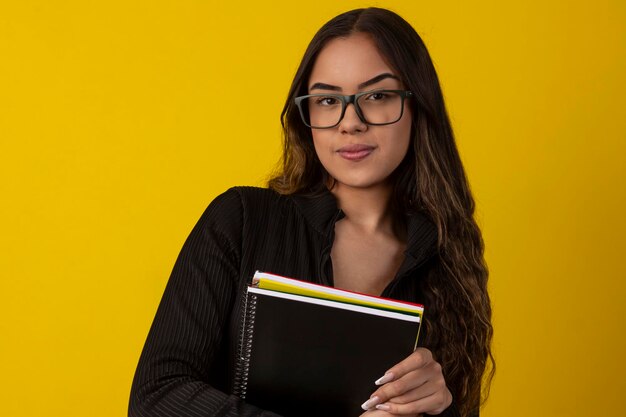 Sexy woman with long curly hair wearing a black textured outfit and holding books and notebooks