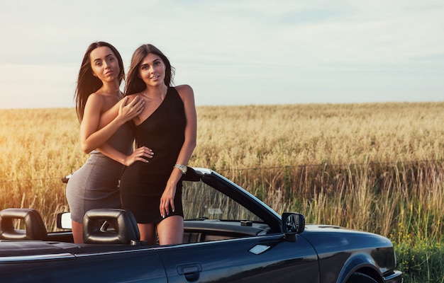 Sexy women posing in a black convertible car