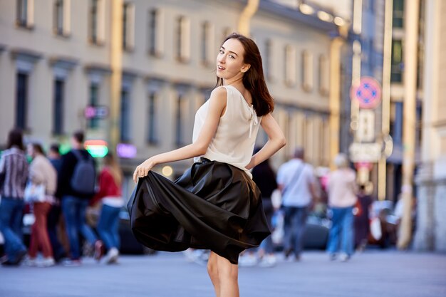 Sexy young female in black skirt walks outdoors