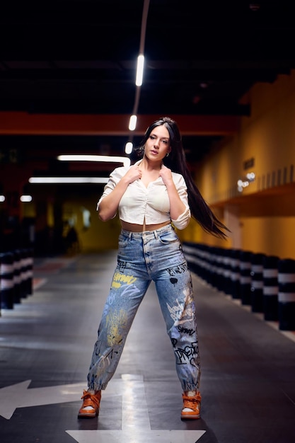 Sexy young girl dressed in jeans yellow bra and black thong in a garage