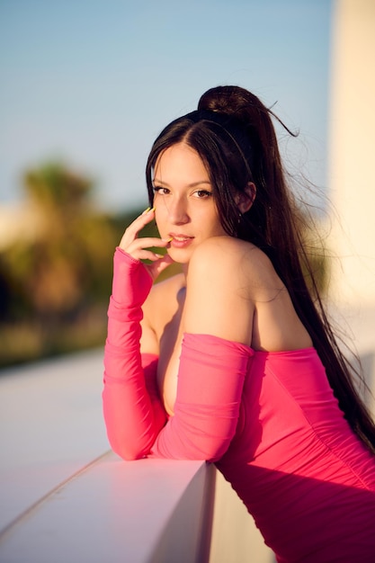 Sexy young girl dressed in a pink dress on a sunny afternoon