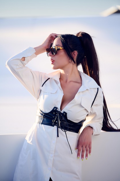 Sexy young girl dressed in a white dress and sunglasses on a sunny afternoon