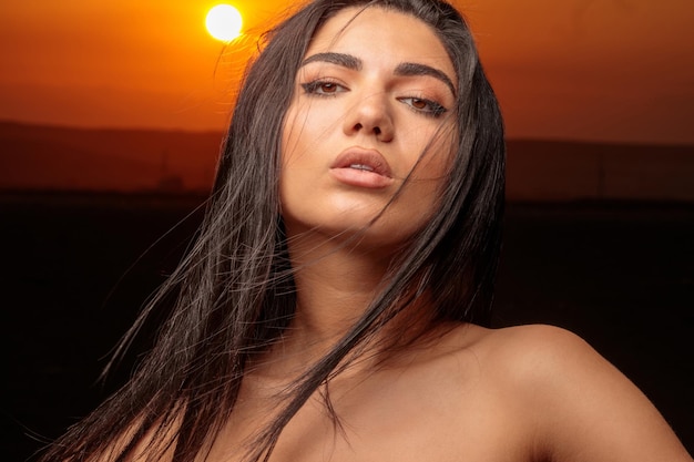 Ragazza sexy che esamina la macchina fotografica durante il tramonto