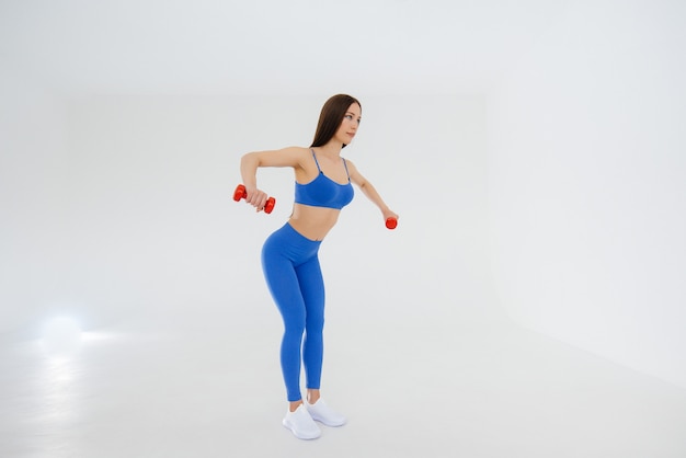 Sexy young girl performs sports exercises on a white space. Fitness, healthy lifestyle.