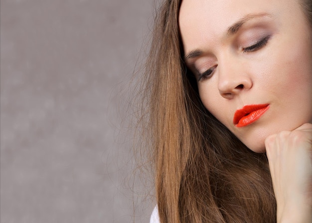 Sexy young lady with long hair and orange lipstick. Closeup