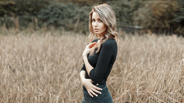 トウモロコシ畑に立っている黒いシャツを着たセクシーな若い女性