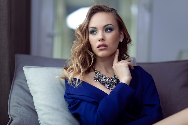 Sexy young woman in a blue jacket with amazing necklace looking aside