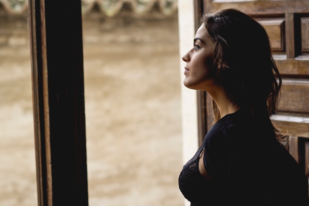 Сексуальная молодая женщина в нижнем белье, стоя рядом с окном