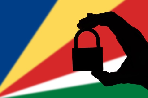 Seychelles security Silhouette of hand holding a padlock over national flag